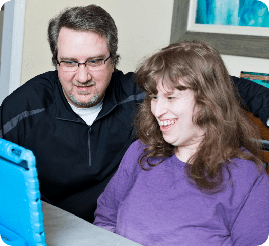Woman with disability and carer looking at iPad