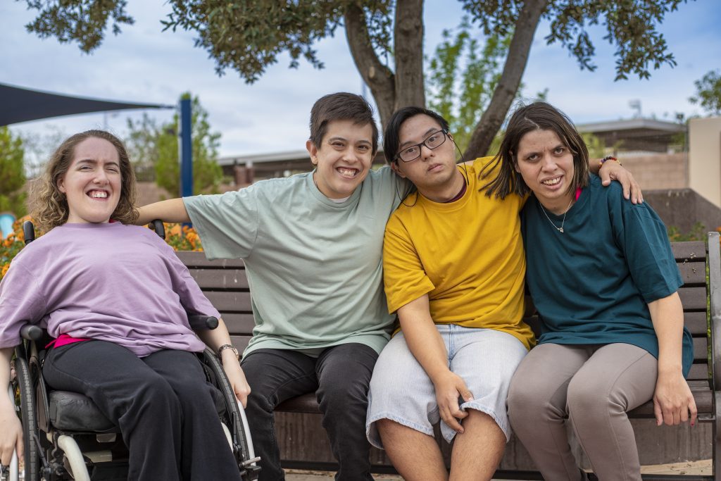 Group of people with disability with arms around each other smiling