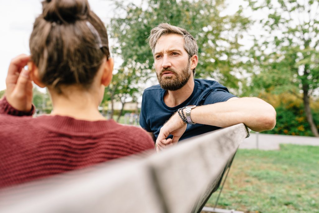 Man and woman having serious conversation on park bench