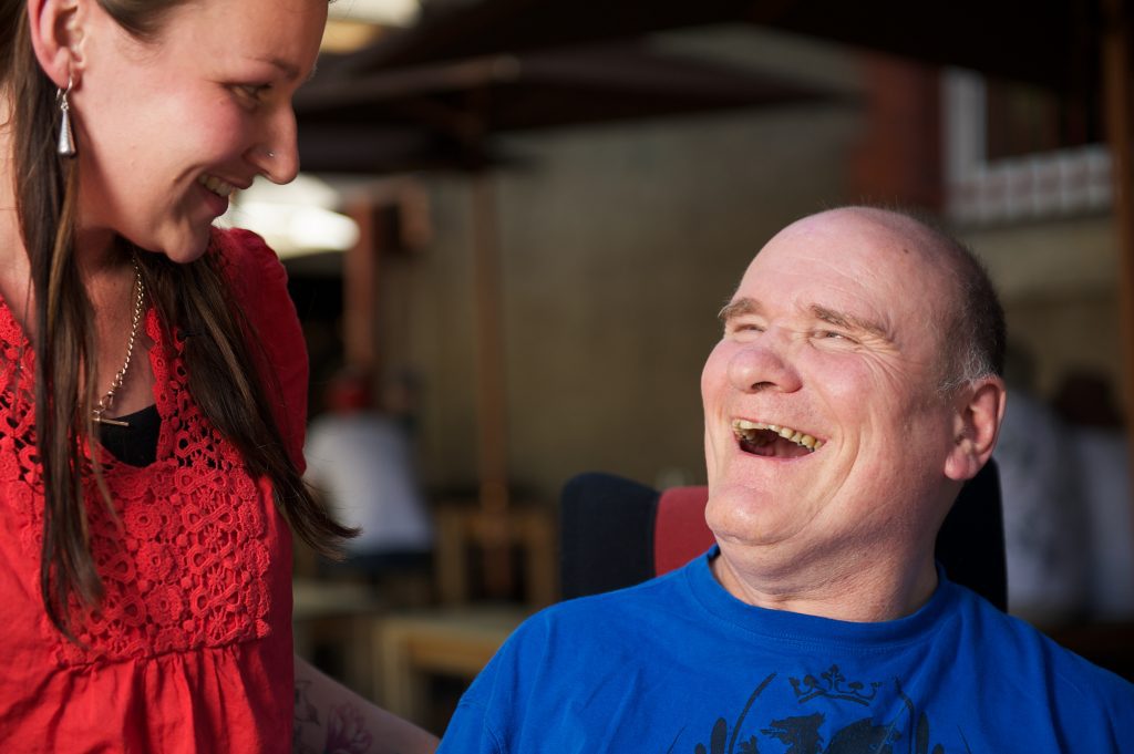 Man with a disability laughing to woman at cafe